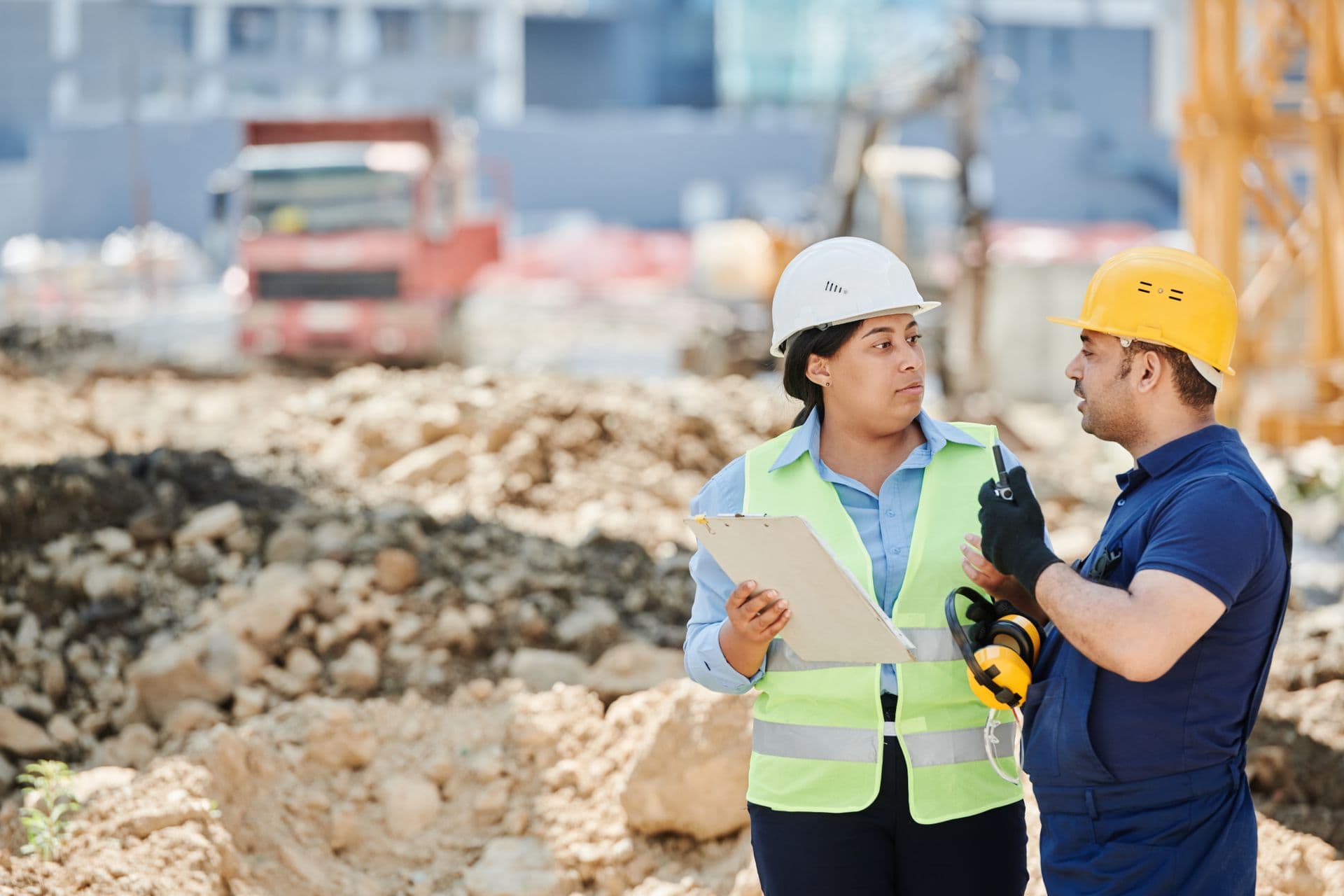 Two workers in hard hats coordinating on an earthworks site