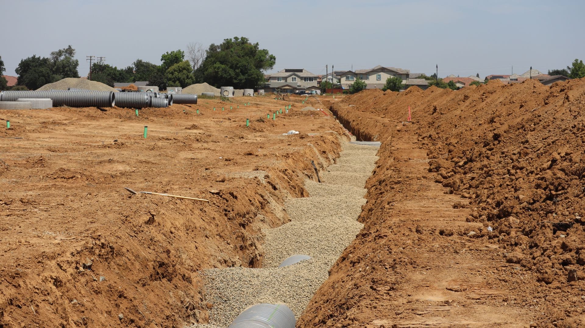 Servicing trench with layout stakes running through a low-rise development