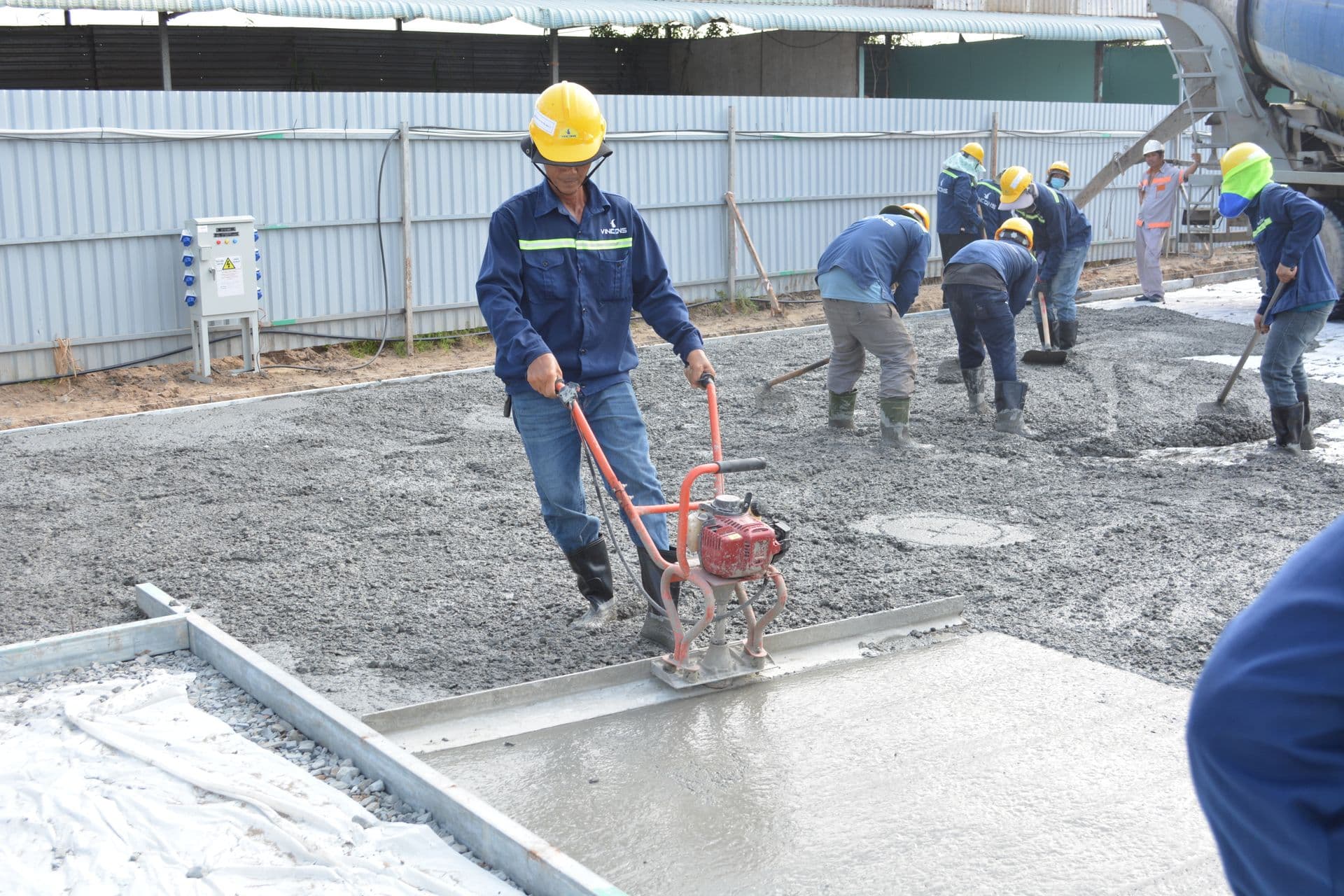 Crew placing and screeding a concrete slab off a mixer truck